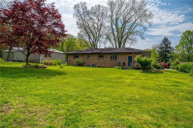 back of property with a yard and brick siding
