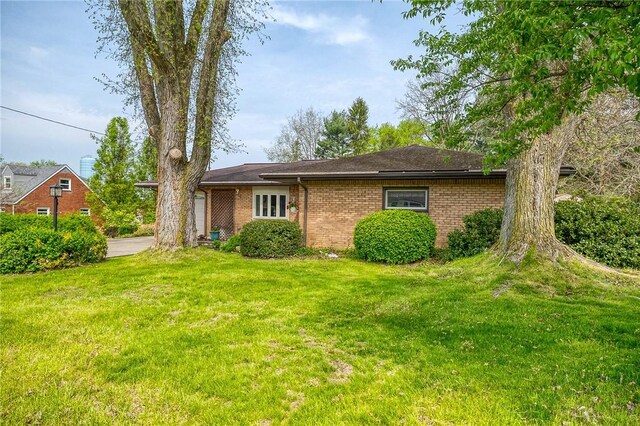 exterior space featuring brick siding and a front yard