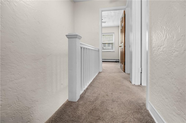 corridor featuring carpet, a textured wall, baseboard heating, and an upstairs landing