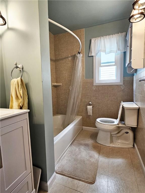 full bath with tile patterned flooring, shower / tub combo with curtain, toilet, and tile walls