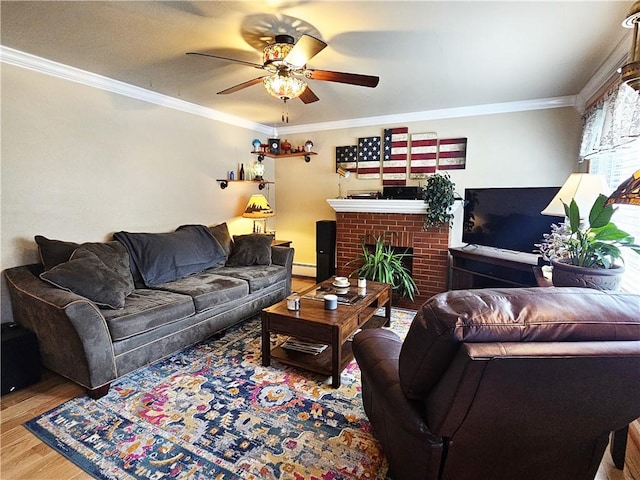 living area with ornamental molding, wood finished floors, a fireplace, a baseboard radiator, and a ceiling fan