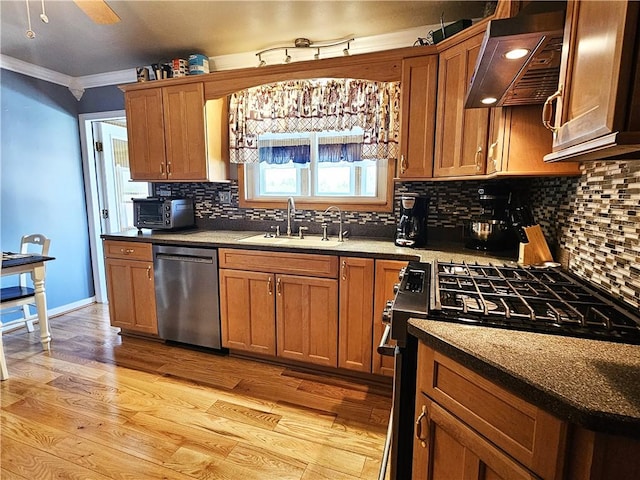 kitchen featuring ornamental molding, gas range, under cabinet range hood, a sink, and dishwasher