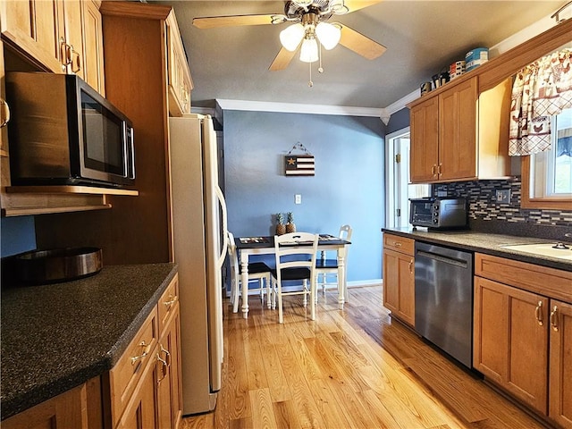 kitchen with appliances with stainless steel finishes, brown cabinetry, a ceiling fan, and backsplash