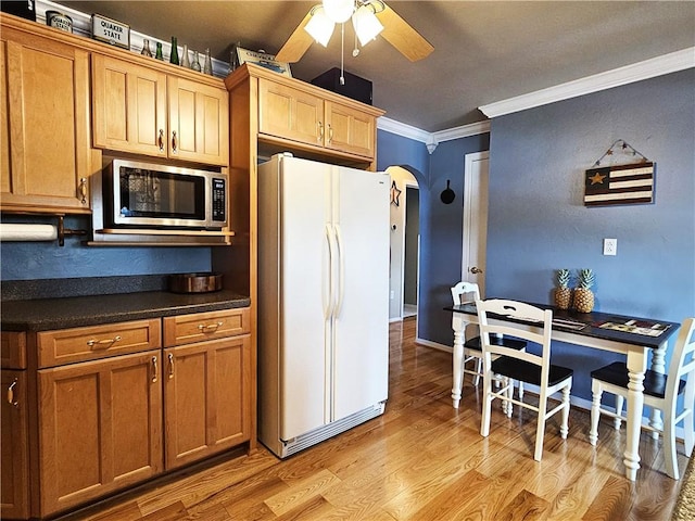 kitchen with dark countertops, ceiling fan, freestanding refrigerator, stainless steel microwave, and ornamental molding