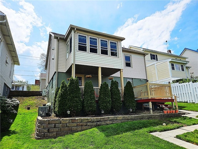 rear view of house featuring fence, a yard, and central AC