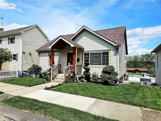 view of front facade featuring a shingled roof and a front lawn