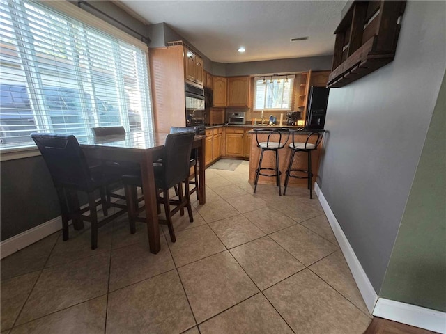 dining room with light tile patterned floors, baseboards, a toaster, and visible vents