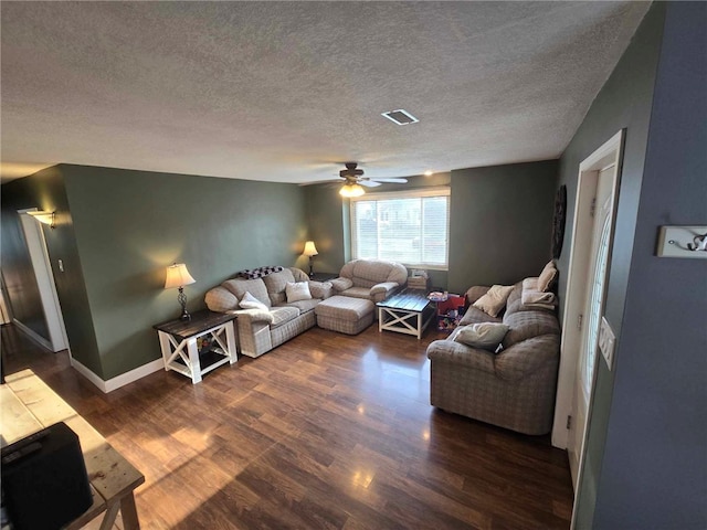 living room featuring a ceiling fan, a textured ceiling, visible vents, and dark wood-style floors