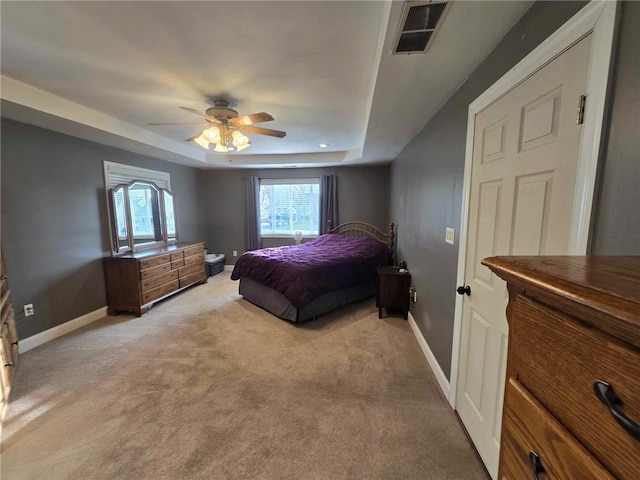 bedroom featuring light colored carpet, a raised ceiling, a ceiling fan, baseboards, and visible vents