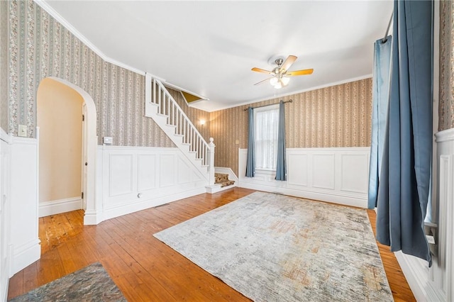 interior space with ceiling fan, wainscoting, and wallpapered walls
