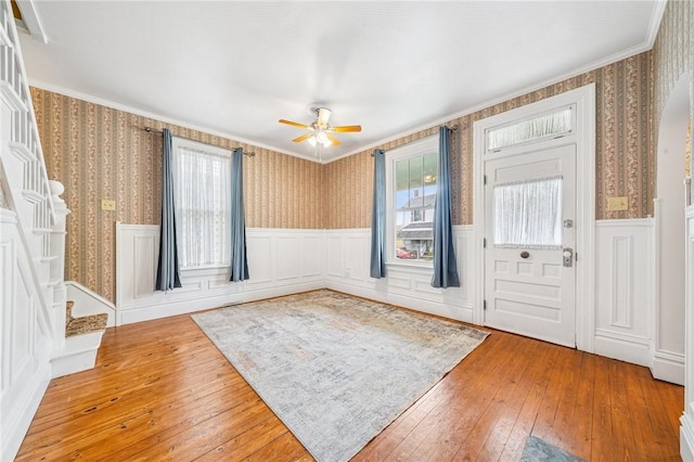 foyer entrance featuring wood-type flooring, wallpapered walls, wainscoting, and a wealth of natural light
