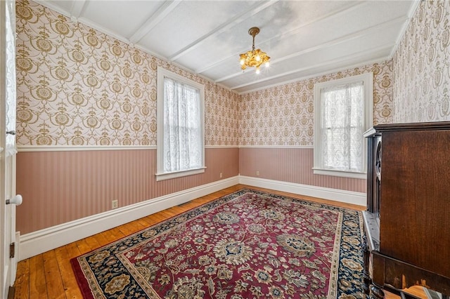 spare room with wood-type flooring, wallpapered walls, and a wealth of natural light