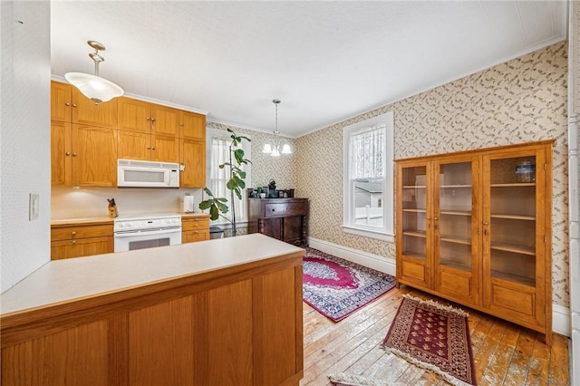 kitchen featuring white appliances, wallpapered walls, ornamental molding, and hardwood / wood-style floors