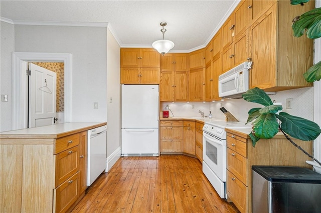 kitchen with crown molding, a peninsula, white appliances, light wood-type flooring, and light countertops