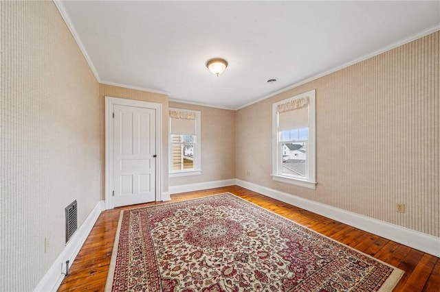 spare room featuring crown molding, baseboards, hardwood / wood-style floors, and visible vents