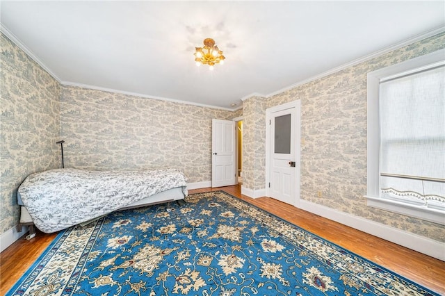bedroom with crown molding, baseboards, wood finished floors, and wallpapered walls
