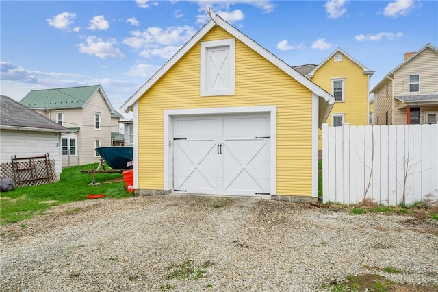 detached garage featuring fence and driveway