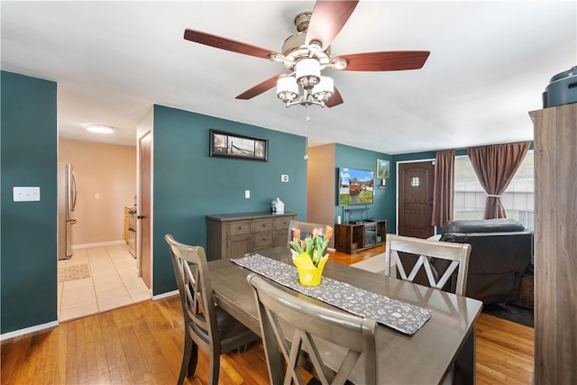 dining area with baseboards, a ceiling fan, and light wood-style flooring
