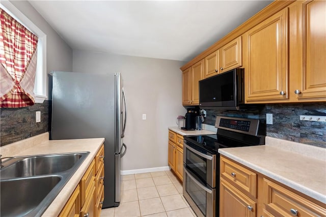 kitchen featuring appliances with stainless steel finishes, a sink, light countertops, decorative backsplash, and light tile patterned floors