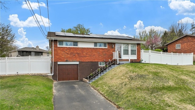 ranch-style home with brick siding, a front lawn, and roof mounted solar panels