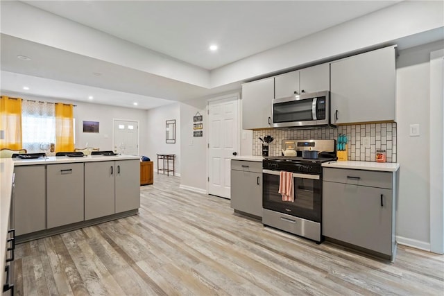 1013 Constance St, East Allegheny, PA 15212 - kitchen with appliances with stainless steel finishes, gray cabinetry, light wood-style flooring, baseboards, and tasteful backsplash