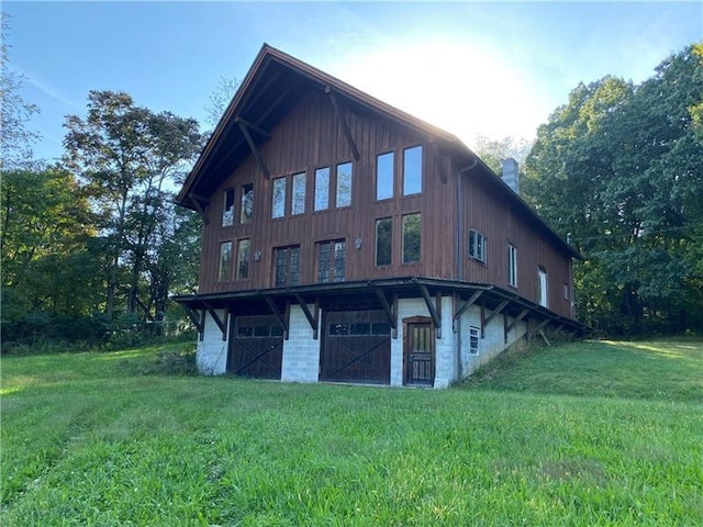 back of house featuring a lawn, a garage, and a chimney