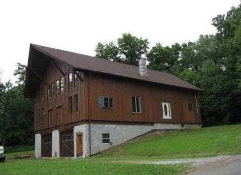 view of side of home featuring a lawn, an attached garage, and a chimney
