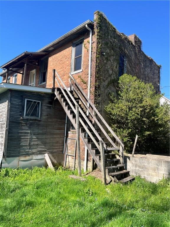 rear view of house featuring stairs and brick siding