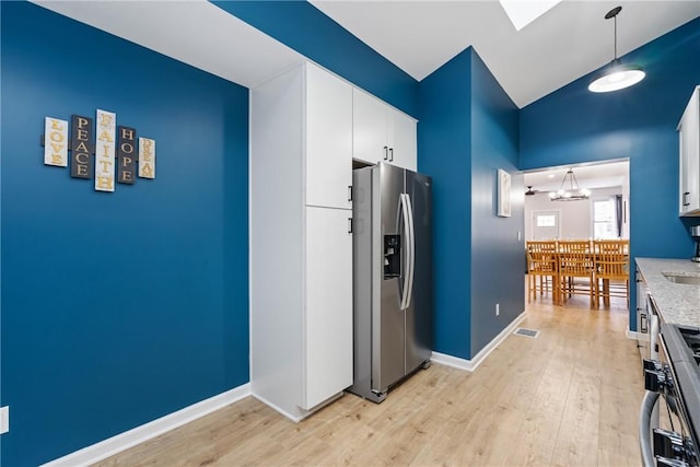 kitchen with pendant lighting, stove, stainless steel fridge with ice dispenser, light wood finished floors, and white cabinetry