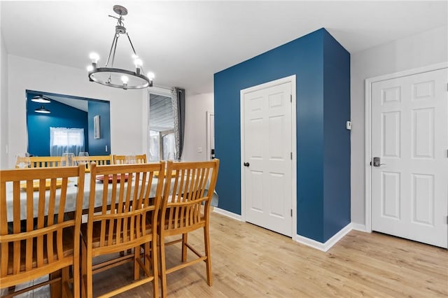 dining space with light wood-type flooring, baseboards, and a chandelier
