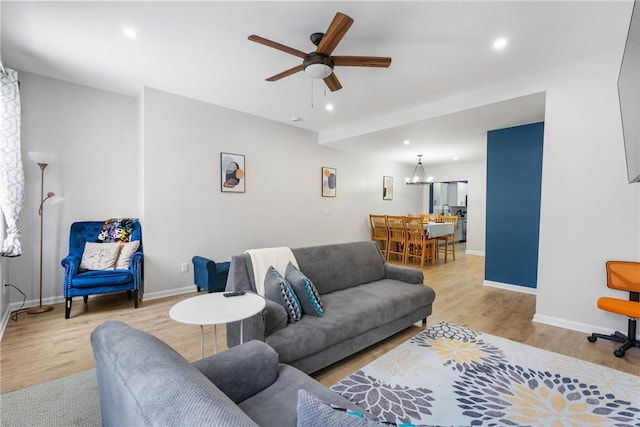 living room featuring baseboards, ceiling fan with notable chandelier, and wood finished floors