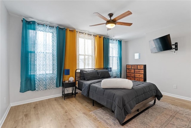 bedroom featuring baseboards, light wood finished floors, and ceiling fan