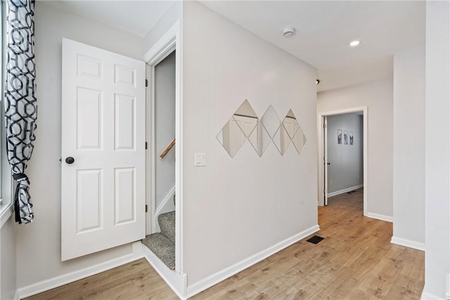 hallway with baseboards, recessed lighting, light wood finished floors, and stairs