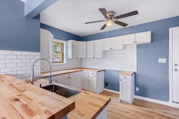 kitchen featuring ceiling fan, wooden counters, tasteful backsplash, white cabinets, and light wood-style flooring