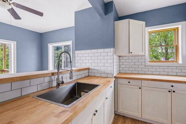 kitchen with a sink, plenty of natural light, backsplash, and butcher block counters