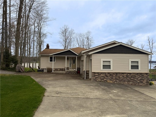 single story home with stone siding, a chimney, and concrete driveway