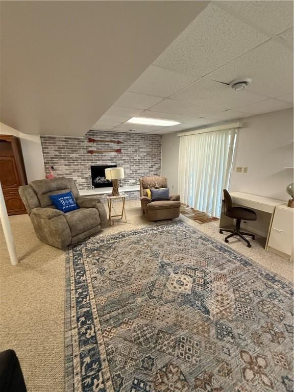 living room with carpet, a brick fireplace, and a paneled ceiling