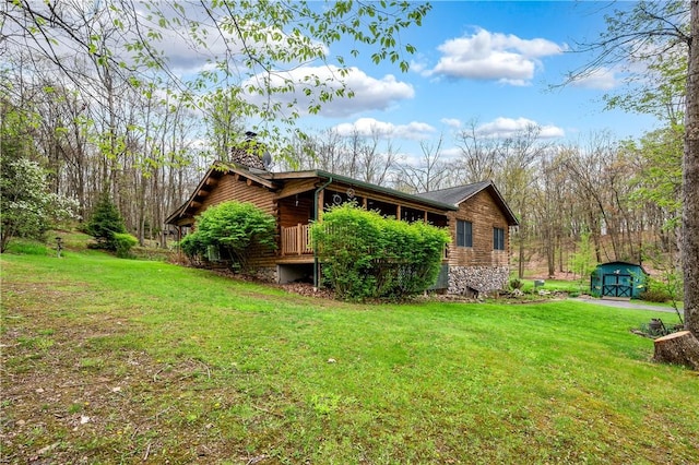 view of side of home featuring a storage shed, a yard, a chimney, and an outdoor structure