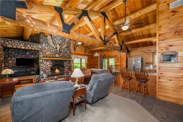 living area featuring wooden walls, vaulted ceiling with beams, visible vents, and wood ceiling