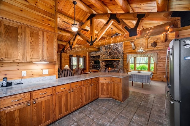 kitchen with freestanding refrigerator, wood walls, a peninsula, a stone fireplace, and wood ceiling