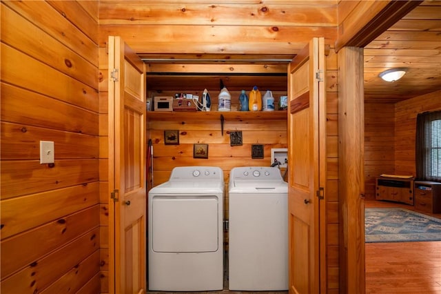 washroom with wooden walls, laundry area, wood finished floors, and washer and dryer