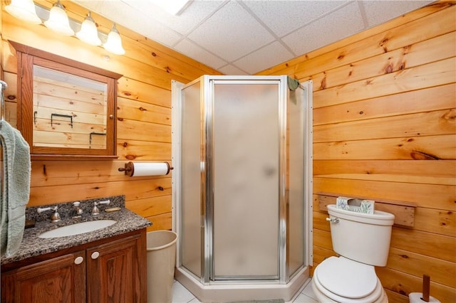 full bathroom with wooden walls, a shower stall, and vanity