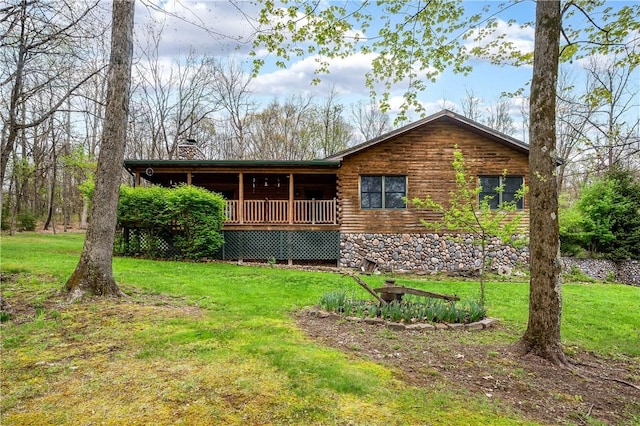 rear view of house featuring a lawn, a chimney, and log siding