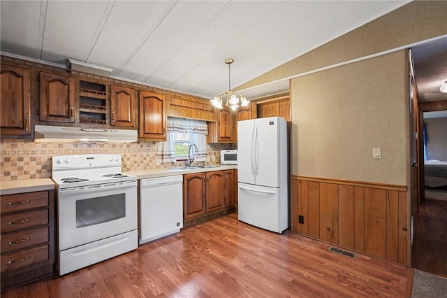 kitchen with a sink, light countertops, under cabinet range hood, and white appliances