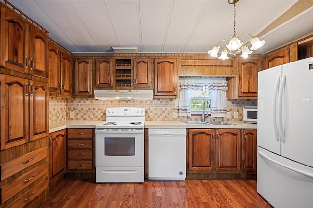 kitchen with white appliances, light countertops, under cabinet range hood, a sink, and a notable chandelier