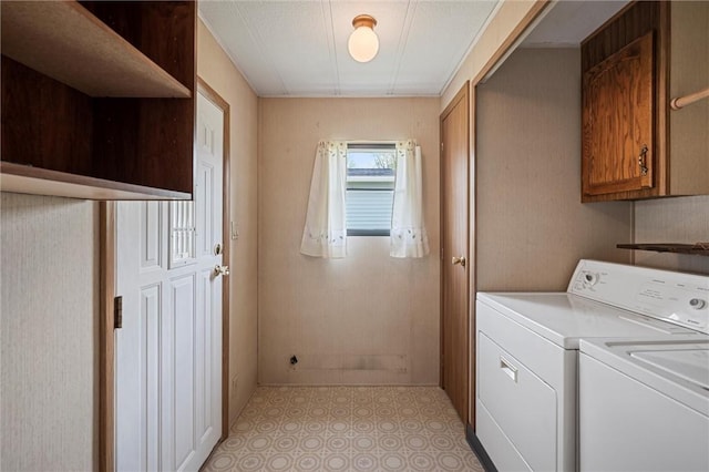 clothes washing area with baseboards, light floors, cabinet space, and washer and dryer