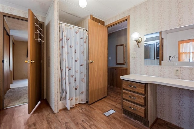 full bath with vanity, wood finished floors, a shower with curtain, and wallpapered walls