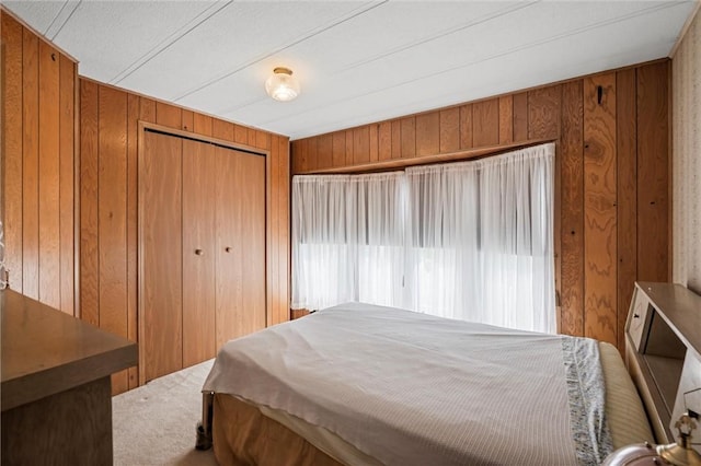 carpeted bedroom featuring a closet and wood walls