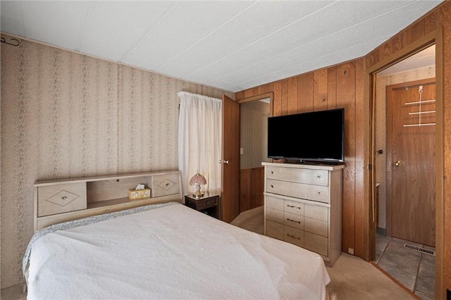carpeted bedroom featuring wooden walls and visible vents