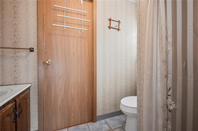 bathroom with vanity, tile patterned floors, toilet, and wallpapered walls